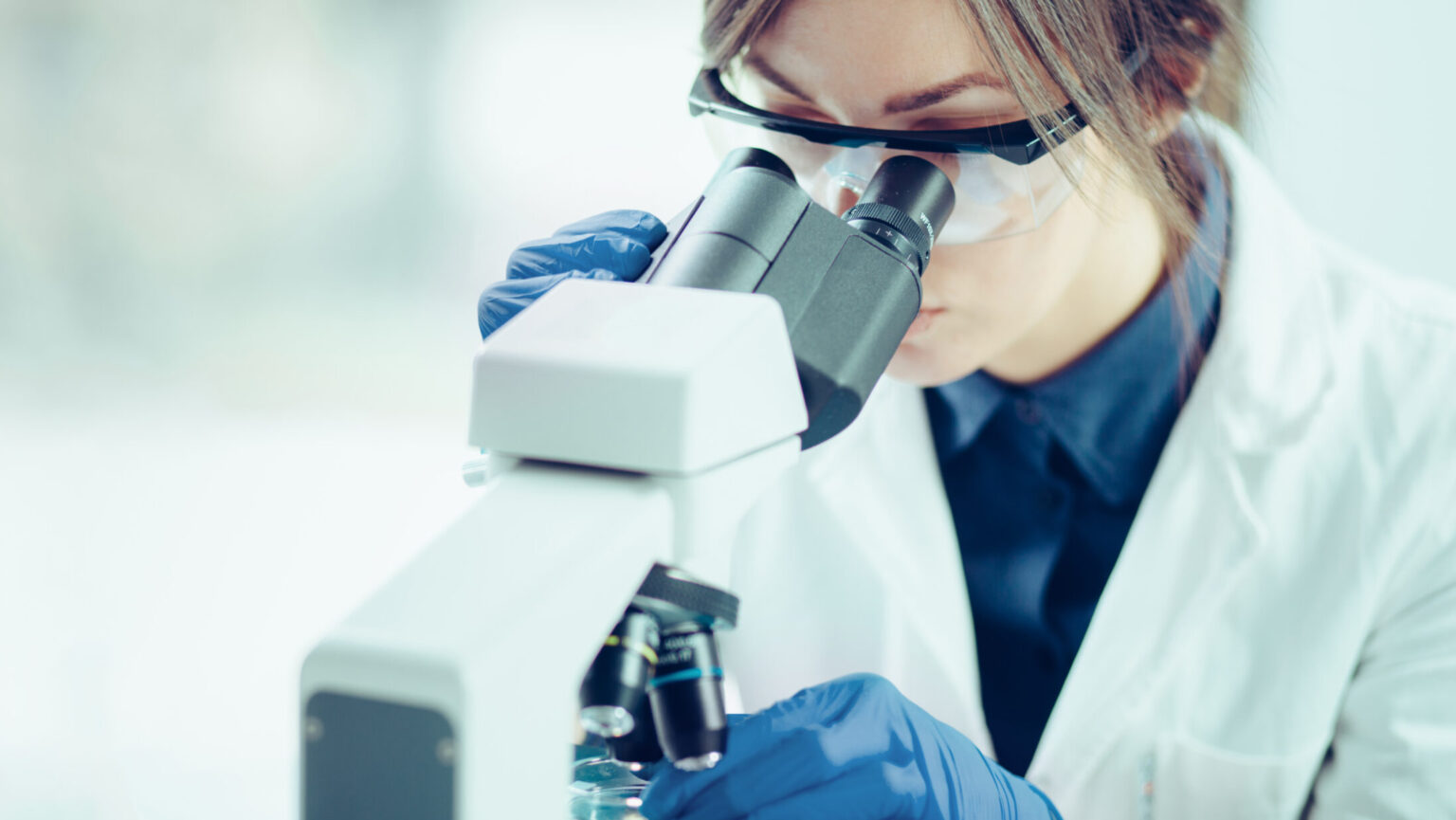 Ung forsker ser gjennom et mikroskop i et laboratorium. Foto.