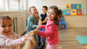 Glad gruppe barn som leker tautrekking i lekerom. Foto